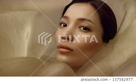 Beauty portrait of Korean woman surrounded by translucent beige silk fabric 137582977