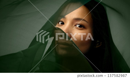 Cinematic beauty portrait of Asian woman emerging from dark green silk fabric Cinematic beauty portrait of Asian woman emerging from dark green silk fabric 137582987