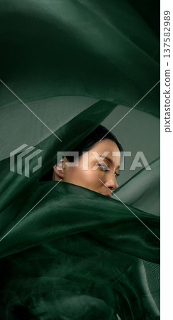 Cinematic portrait of Korean woman partially hidden in flowing green silk fabric Cinematic portrait of Korean woman partially hidden in flowing green silk fabric 137582989