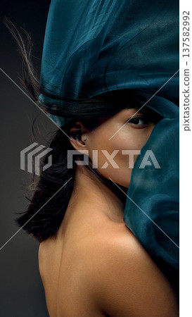 Korean woman framed by moving teal silk fabric expressing freedom, elegance and luxury. 137582992