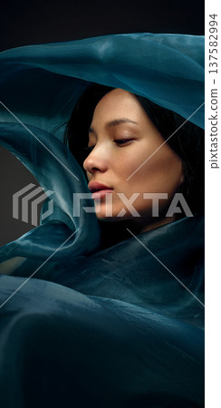 Elegant beauty portrait of Korean woman surrounded by sculptural teal silk fabric 137582994