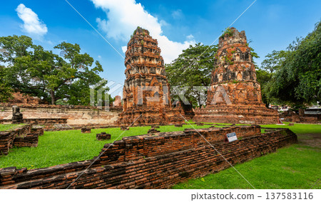 Ancient stupa towers in Ayutthaya historical park, Thailand. Ruins of former Siam capital under blue sky on sunny day. Famous travel destination with cultural heritage and Buddhist history. Ancient stupa towers in Ayutthaya historical park, Thailand. Ruins of former Siam capital under blue sky on sunny day. Famous travel destination with cultural heritage and Buddhist history. 137583116