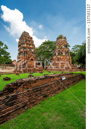 Ancient stupa towers in Ayutthaya historical park, Thailand. Ruins of former Siam capital under blue sky on sunny day. Famous travel destination with cultural heritage and Buddhist history. Ancient stupa towers in Ayutthaya historical park, Thailand. Ruins of former Siam capital under blue sky on sunny day. Famous travel destination with cultural heritage and Buddhist history. 137583117