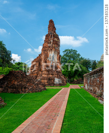 Ancient stupa towers in Ayutthaya historical park, Thailand. Ruins of former Siam capital under blue sky on sunny day. Famous travel destination with cultural heritage and Buddhist history. 137583128