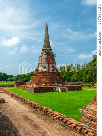 Ancient stupa towers in Ayutthaya historical park, Thailand. Ruins of former Siam capital under blue sky on sunny day. Famous travel destination with cultural heritage and Buddhist history. 137583129