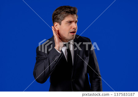 Mature Businessman Pointing To Ear With Confused Face, Signaling He Cant Hear Mature Businessman Pointing To Ear With Confused Face, Signaling He Cant Hear 137583187