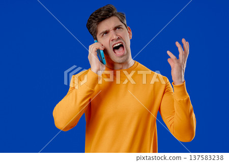 Angry Handsome Man Quarreling, Screaming Talking On Mobile Phone. Guy In Studio Angry Handsome Man Quarreling, Screaming Talking On Mobile Phone. Guy In Studio 137583238