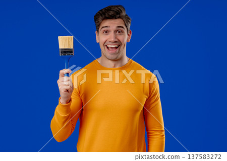 Happy Man Holding Paint Brush Ready for Home Renovation. Creativity manual work. 137583272