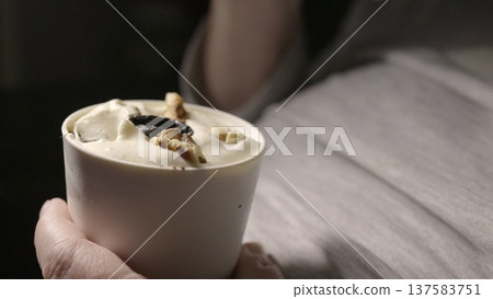 A creamy dessert with nuts and prunes in hand on his stomach. A creamy dessert with nuts and prunes in hand on his stomach. 137583751