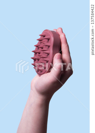 Hair pink scalp massager in woman hand on the pink background isolated. Image with copy space. Mock up for design and banner. Vertical Hair pink scalp massager in woman hand on the pink background isolated. Image with copy space. Mock up for design and banner. Vertical 137584422