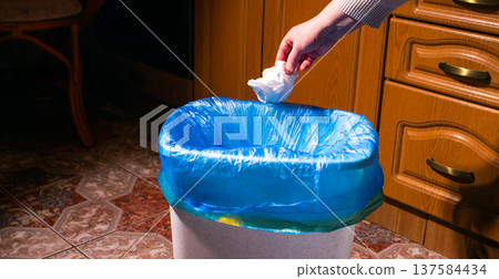 Woman throwing garbage into trash bin in kitchen 137584434