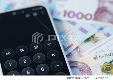 Smartphone with a calculator app on the screen over Ukrainian hryvnia banknotes (UAH) Smartphone with a calculator app on the screen over Ukrainian hryvnia banknotes (UAH) 137584538