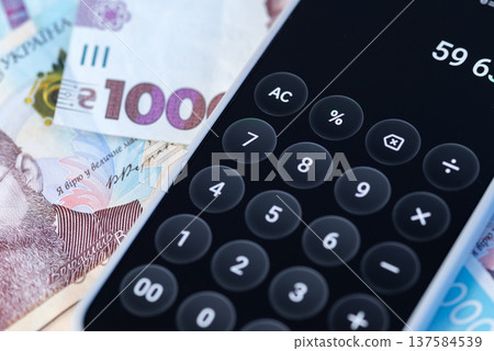 Smartphone calculator app with Ukrainian hryvnia banknotes, mobile finance and money calculation concept Smartphone calculator app with Ukrainian hryvnia banknotes, mobile finance and money calculation concept 137584539