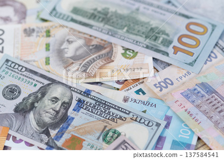 Mixed US dollars and Ukrainian hryvnia banknotes background, international currency and finance concept. Mixed US dollars and Ukrainian hryvnia banknotes background, international currency and finance concept. 137584541
