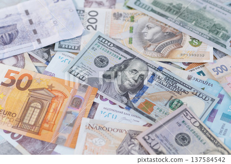 Top view of mixed global currencies including US Dollars, Euro, Polish Zloty, and Ukrainian Hryvnia banknotes Top view of mixed global currencies including US Dollars, Euro, Polish Zloty, and Ukrainian Hryvnia banknotes 137584542