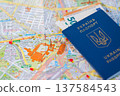 Ukrainian biometric passport with Euro banknotes lying on a travelling map of Berlin, Germany. 137584543