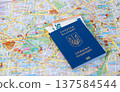 Ukrainian biometric passport with Euro banknotes lying on a travelling map of Berlin, Germany. 137584544
