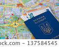 Ukrainian biometric passport with Euro banknotes lying on a travelling map of Berlin, Germany. 137584545