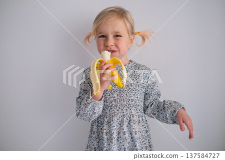 Little 4 Year Old Girl Eating Banana on White Background Little 4 Year Old Girl Eating Banana on White Background 137584727