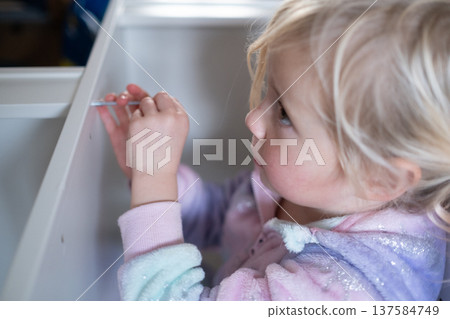 Independent 4 year old girl assembling furniture with a screwdriver in a modern home interior Independent 4 year old girl assembling furniture with a screwdriver in a modern home interior 137584749