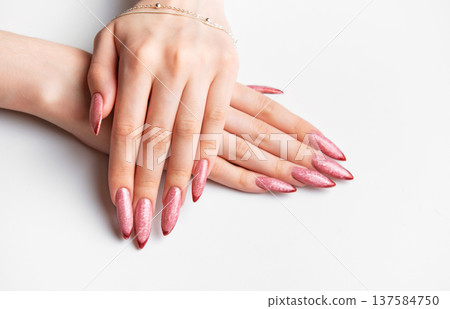 Woman's hands showing long pink glitter fingernails manicure with jewelry 137584750