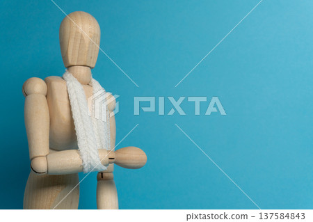 Wooden figure with a white scarf against a blue background in a simple indoor setting 137584843