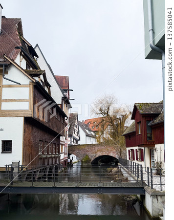 A tranquil canal in the fishermans quarter of Ulm, Germany. Reflections of colorful buildings line the waters edge, creating a serene urban scene. A tranquil canal in the fishermans quarter of Ulm, Germany. Reflections of colorful buildings line the waters edge, creating a serene urban scene. 137585041