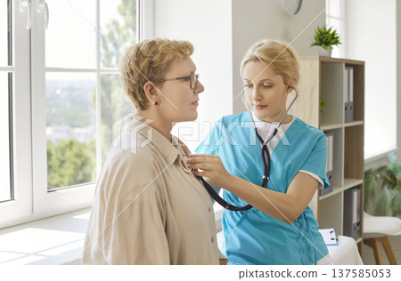 Female nurse performing stethoscope examination on senior patient in modern clinic Female nurse performing stethoscope examination on senior patient in modern clinic 137585053