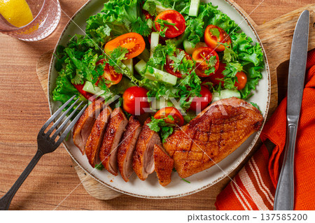 Delicious grilled duck breast served with fresh garden salad and cherry tomatoes at a rustic dining table Delicious grilled duck breast served with fresh garden salad and cherry tomatoes at a rustic dining table 137585200