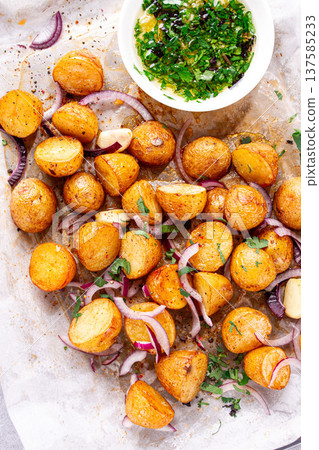 young baked potatoes, with chopped herbs and onions, cooked on a baking sheet, in the kitchen young baked potatoes, with chopped herbs and onions, cooked on a baking sheet, in the kitchen 137585233