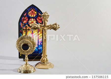 Gold monstrance, crucifix, and stained glass window on a light background Gold monstrance, crucifix, and stained glass window on a light background 137586115