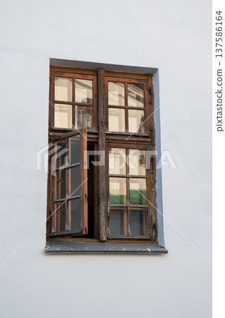 Open wooden window with glass panes in white building facade reflecting surrounding architecture, daylight. Image suitable for concepts of architecture detail, urban renovation, real estate exterior Open wooden window with glass panes in white building facade reflecting surrounding architecture, daylight. Image suitable for concepts of architecture detail, urban renovation, real estate exterior 137586164