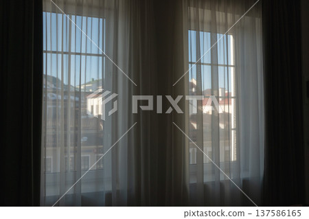 Hotel room window with sheer curtains and city view through glass in modern accommodation interior. Travel stay, hospitality design, urban hotel comfort, tourism lodging Hotel room window with sheer curtains and city view through glass in modern accommodation interior. Travel stay, hospitality design, urban hotel comfort, tourism lodging 137586165