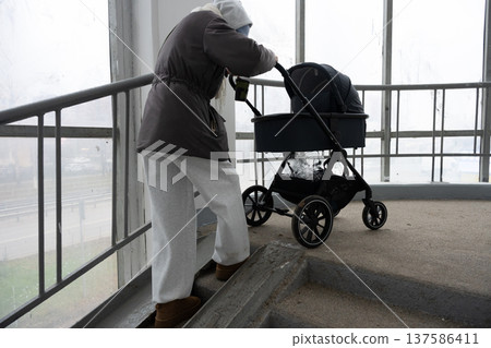 Mother navigating stairs with baby stroller representing challenges Mother navigating stairs with baby stroller representing challenges 137586411