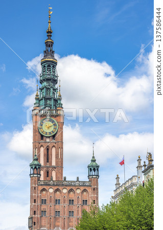The Main Town Hall in Gdansk, a city on the Baltic coast of northern Poland, Europe. Historic clock tower rises against a cloudy blue sky, showcasing intricate architecture. 137586444