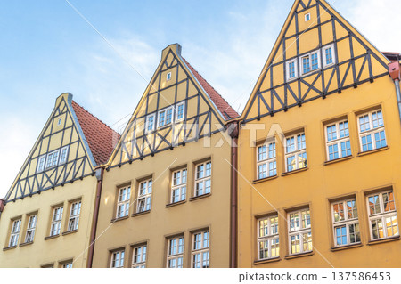 Gdansk, a city on the Baltic coast of northern Poland, Europe. Historic yellow buildings with gable roofs showcase classic European architecture against a blue sky. Old town charm and design. Gdansk, a city on the Baltic coast of northern Poland, Europe. Historic yellow buildings with gable roofs showcase classic European architecture against a blue sky. Old town charm and design. 137586453