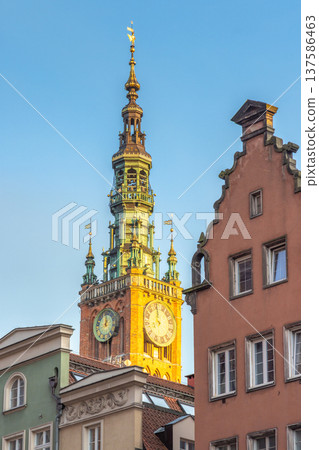 Gdansk, a city on the Baltic coast of northern Poland, Europe. Historical architecture is showcased in this view of a clock tower rising above colorful buildings against a clear blue sky backdrop. 137586463