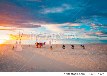 Radiant sunset beach wedding with romantic candles and flowers colorful sky and clouds pristine ocean serene summer landscape perfect honeymoon anniversary destination 137587324