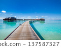 Radiant Maldives sunny water villas with wooden pier under bright blue sky calm turquoise ocean serene tropical paradise summer vacation scenic travel destination 137587327