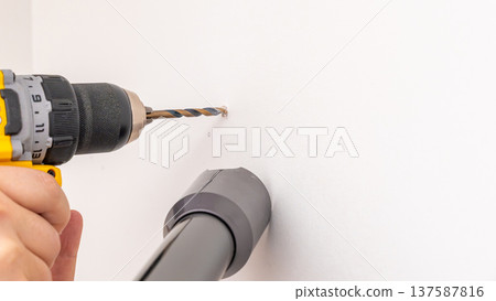 Mans hands positioning white shelf plank onto black metal bracket attached to white wall. Home improvement, placing shelf board, DIY shelf assembly, fitting process. 137587816