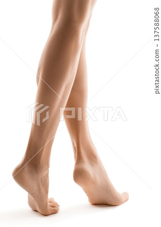 Woman's legs and feet stand delicately on a white surface, showcasing beauty and health Woman's legs and feet stand delicately on a white surface, showcasing beauty and health 137588068
