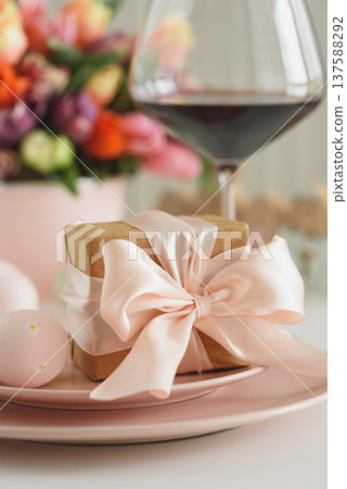 Easter Table Setting with Gift Box, Decorated Eggs, Wine Glass and Tulips. Festive Spring Lifestyle Easter Table Setting with Gift Box, Decorated Eggs, Wine Glass and Tulips. Festive Spring Lifestyle 137588292