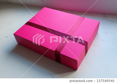 A pink box with a red ribbon on it A pink box with a red ribbon on it 137589540