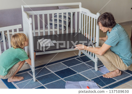 Father and older brother assembling a baby crib at home, preparing for a newborn arrival. Warm family moment full of care and anticipation. Parenthood, sibling bond and home preparation concept Father and older brother assembling a baby crib at home, preparing for a newborn arrival. Warm family moment full of care and anticipation. Parenthood, sibling bond and home preparation concept 137589630