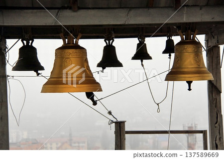 Large golden church bells hanging in a wooden bell tower, viewed from below 137589669