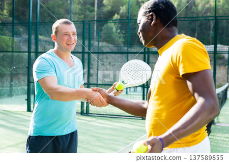 Two men padel tennis players shake hands amicably 137589855