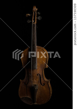 Old wooden violin showcased against a dark background highlighting its craftsmanship and vintage appeal Old wooden violin showcased against a dark background highlighting its craftsmanship and vintage appeal 137590309