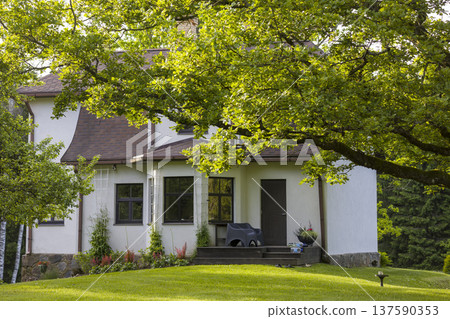Charming countryside home surrounded by lush greenery in the afternoon light 137590353