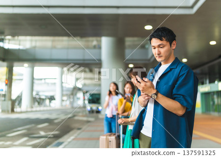 一名男子正在等候,他正在使用智慧型手機。照片由關西國際機場(KIX)提供。 一名男子正在等候,他正在使用智慧型手機。照片由關西國際機場(KIX)提供。 137591325