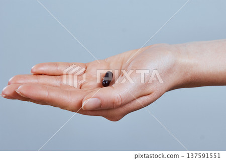 Hand holding black activated carbon capsule for food poisoning treatment - Image.Vitamins And Dietary Supplements. Hand holding black activated carbon capsule for food poisoning treatment - Image.Vitamins And Dietary Supplements. 137591551
